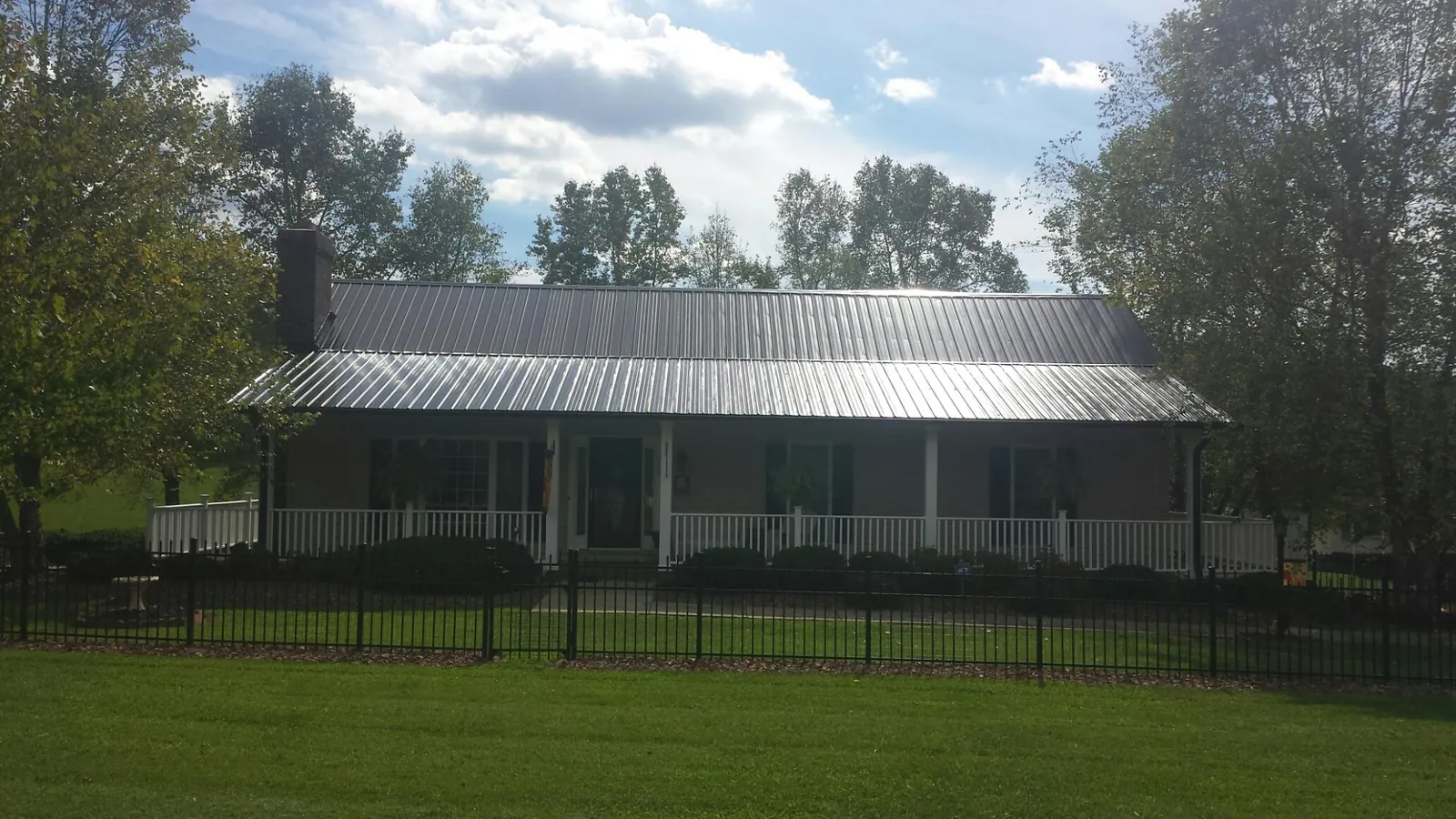 Gray metal roof on a brick ranch with a full width front porch — Gutter Guard Installation work by our crew in Bethune